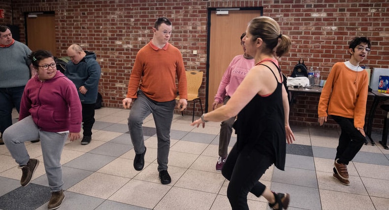 Des jeunes en situation de handicap mental pratiquent des activités sportives adaptées avec un entraineur dans une salle