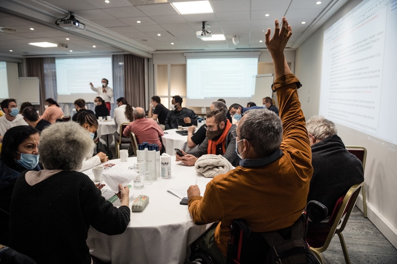 Conférence Citoyenne sur l'aide, l'entraide et les solidarités, 2021 - Réunion plénière : un participant lève la main pour demander la parole