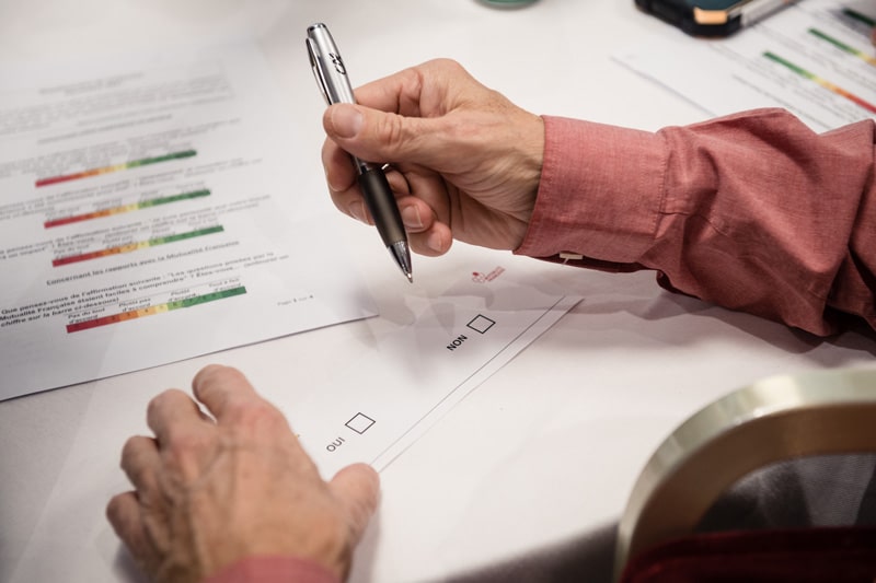 Conférence Citoyenne sur l'aide, l'entraide et les solidarités, 2021 - Plan rapproché sur les mains d'un participant qui prend des notes